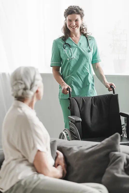 ragazza in camice asa che aiuta una signora anziana in carrozzina