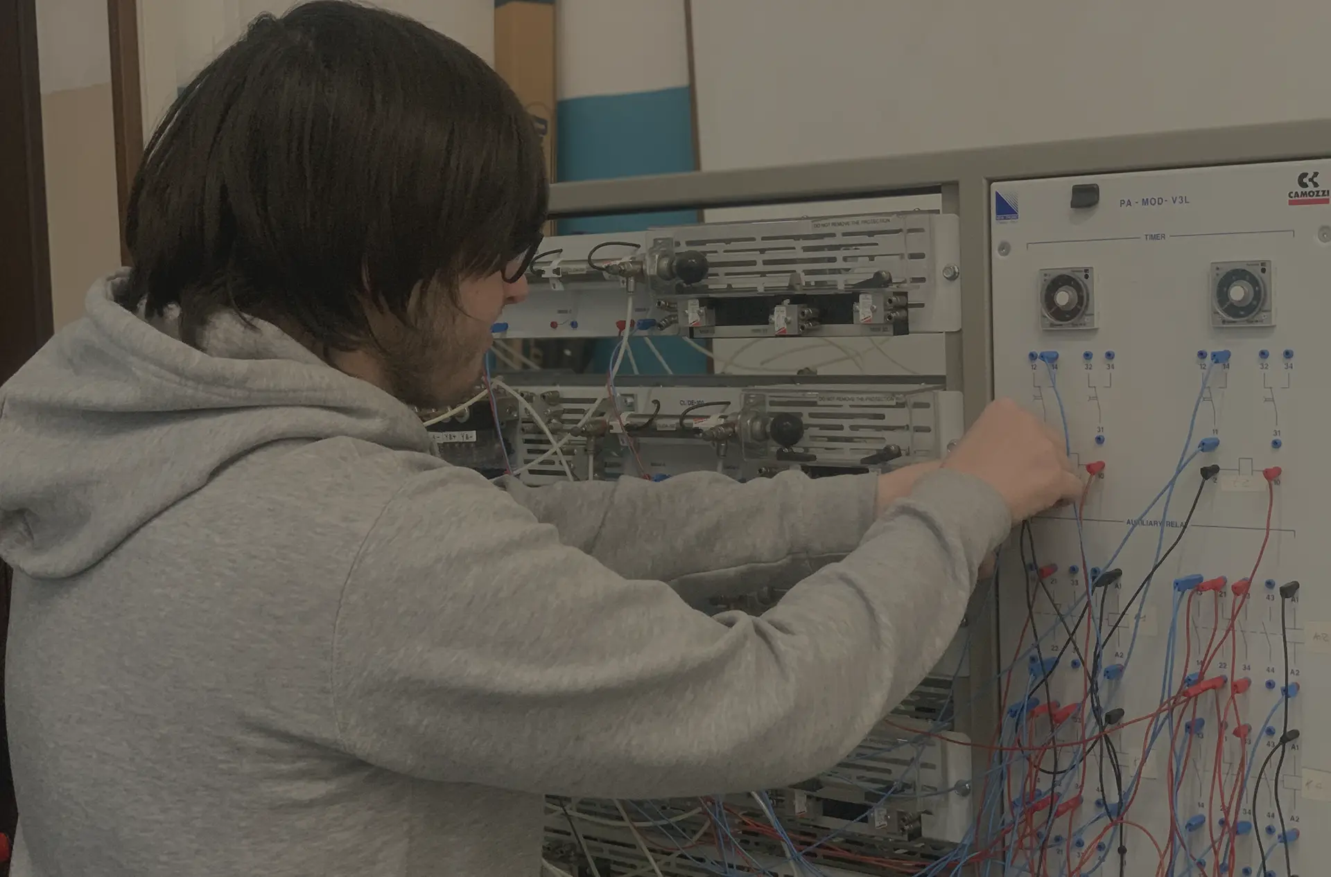 Studente che lavora su un pannello di controllo con fili e componenti elettrici.