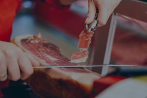 Operatore affetta del prosciutto crudo con un coltello