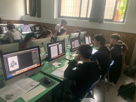 Studenti in aula informatica lavorano su progetti grafici al computer.