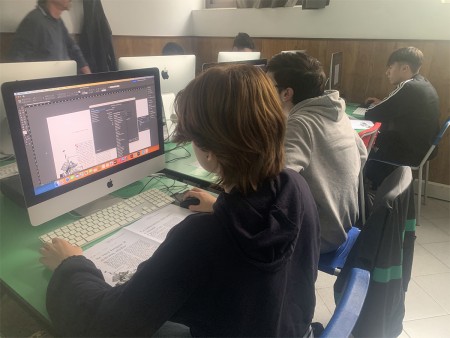 Studente lavora al computer su un progetto di grafica in aula informatica.