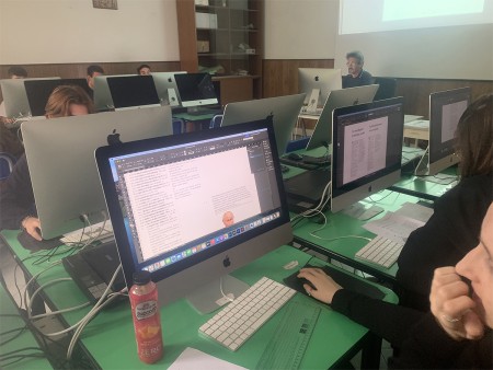 Studenti lavorano su progetti di impaginazione grafica al computer in aula informatica.