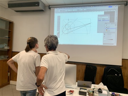 Insegnante e studente osservano una proiezione di grafica vettoriale.