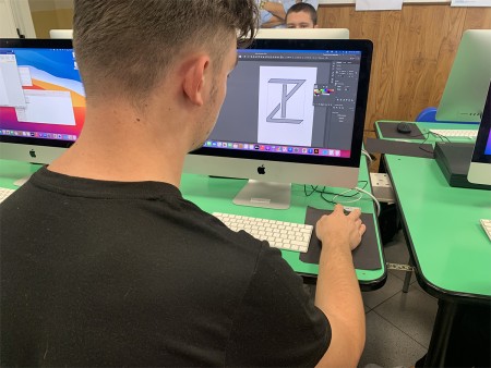 Studente al computer che lavora su un progetto grafico, utilizzando un software di progettazione.