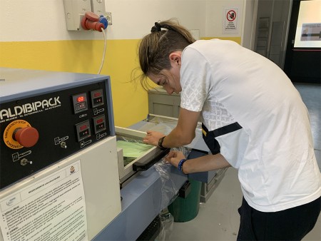 Studente utilizza una macchina per il confezionamento di materiale didattico in laboratorio.