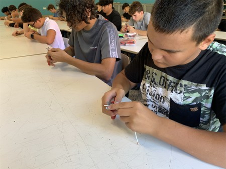 Studenti lavorano con strumenti manuali al tavolo.