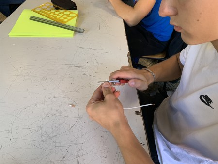 Studente utilizza un attrezzo manuale per lavorare su un filo elettrico.