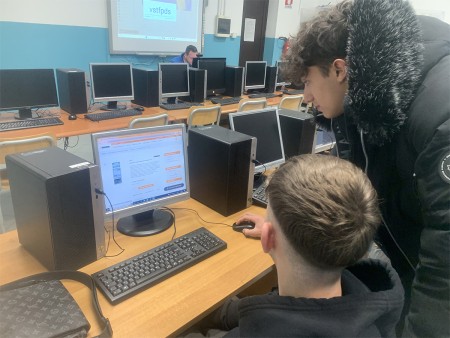 Due studenti stanno lavorando insieme davanti a un computer, concentrati su ciò che è visualizzato sullo schermo. Uno di loro utilizza il mouse, mentre l'altro osserva attentamente.