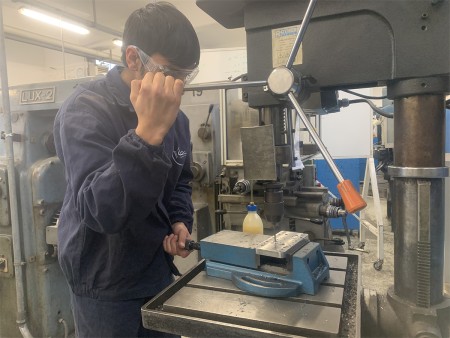  Uno studente indossa occhiali protettivi mentre utilizza una macchina utensile nel laboratorio, dimostrando l'importanza della sicurezza durante le attività pratiche.